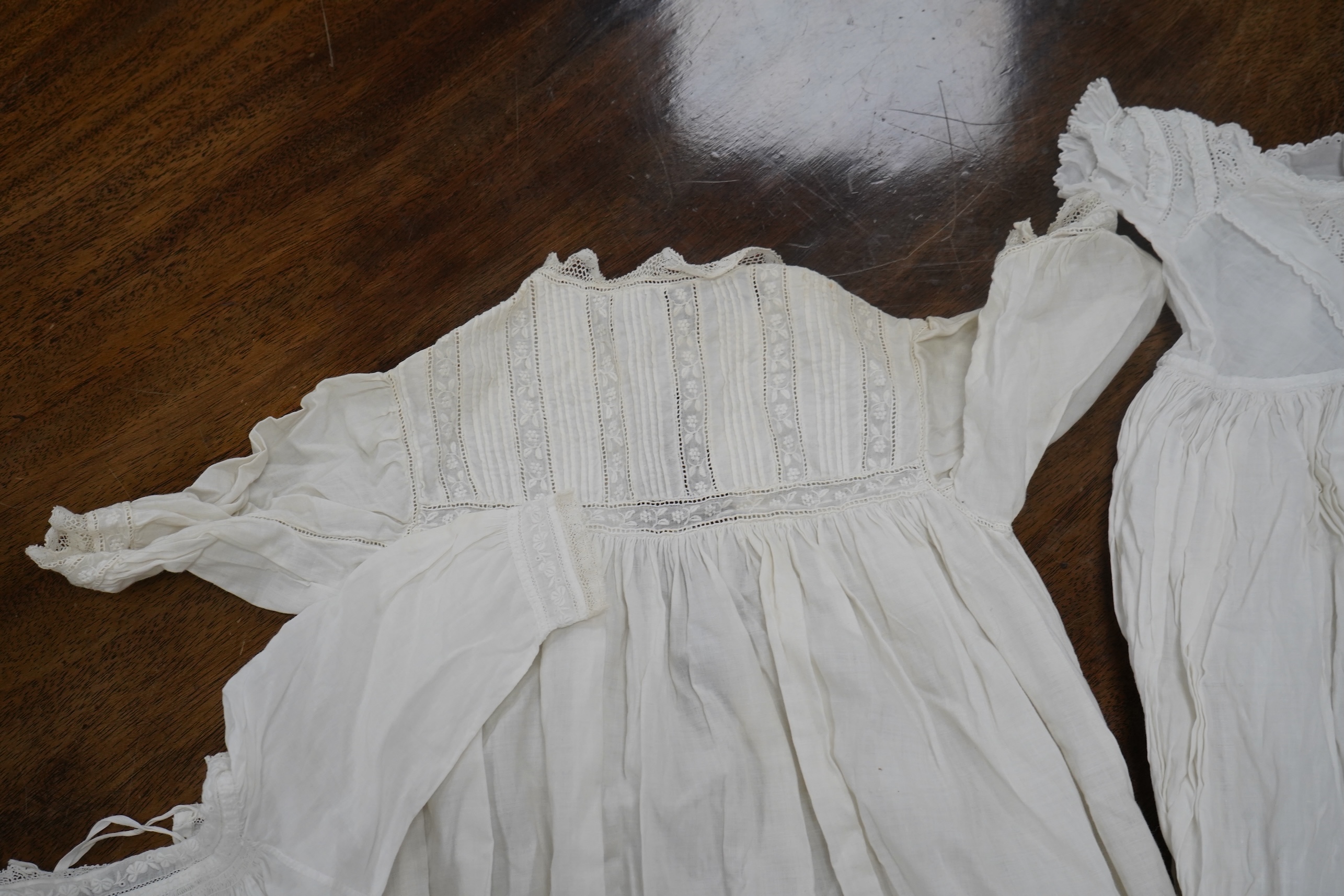 Two late 19th early 20th century long baby night gowns and two shorter baby gowns, together with a pink satin ladies full length slip and a similar cream silk stockinette slip, the bodices worked on baby dresses are embr